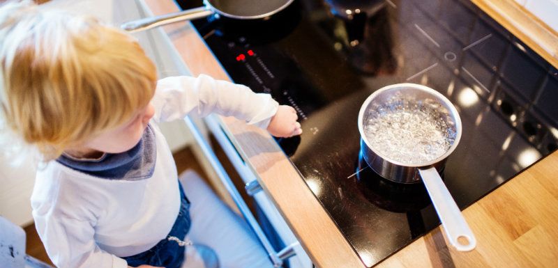 Garçon enfant en bas âge dans une situation dangereuse proche des plaques de cuisson